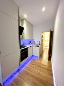 a kitchen with white cabinets and a wooden floor at Brand New Modern Flat in Southall