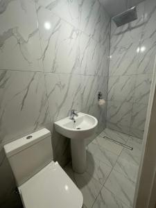 a white bathroom with a toilet and a sink at Brand New Modern Flat in Southall