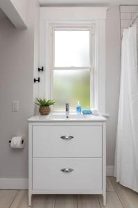 een witte badkamer met een wastafel en een raam bij Deluxe 4-Bedroom w Huge Deck 3-Min to Downtown in Cincinnati