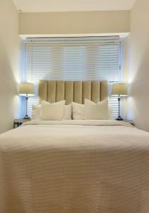 duże łóżko z białymi poduszkami i oknem w obiekcie Brand New Modern Flat w mieście Southall