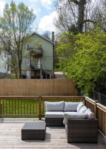 een patio met een bank en stoelen aan een hek bij Deluxe 4-Bedroom w Huge Deck 3-Min to Downtown in Cincinnati