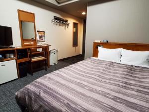 een hotelkamer met een bed en een televisie bij Hotel Route-Inn Kameyama Inter in Kameyama