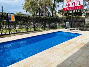 a swimming pool with a chair next to a fence at Port Stephens Motel in Nelson Bay
