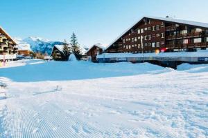 um terreno coberto de neve com um edifício ao fundo em Superbe studio Anzère, rénové, au pied des pistes em Anzère