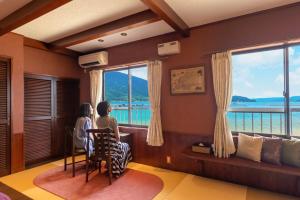 duas pessoas sentadas numa mesa a olhar pela janela em Tsuruga Sazanami Resort Chobei em Tsuruga