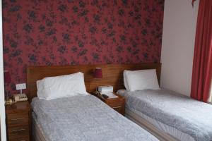 two beds in a hotel room with red wallpaper at Kirkdale Hotel in Croydon