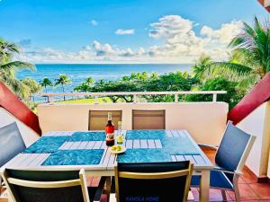 a table on a balcony with a view of the ocean at KANOLA Home in Sainte-Anne