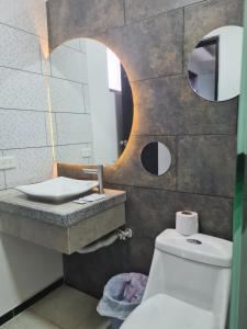a bathroom with a sink and a toilet and a mirror at HOSTERIA PUERTO BALBANERA in Tonsupa