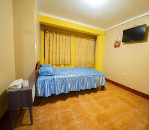 HOSTAL TARAPACA في هانوكو: غرفة نوم صغيرة بها سرير وتلفزيون