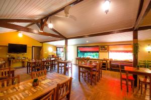 a restaurant with wooden tables and chairs and a television at ECO RESORT FASCINAÇÃO in Miguel Pereira