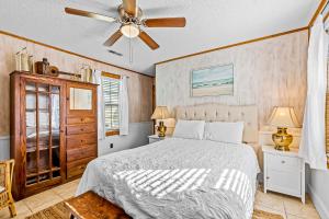 Charming Cottage في أتلانتيك بيتش: غرفة نوم بسرير ومروحة سقف