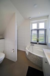 een badkamer met een bad, een toilet en een raam bij Buitenplaats Welsdael in Margraten