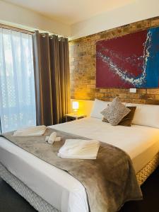 una camera con un grande letto con un muro di mattoni di Port Stephens Motel a Nelson Bay