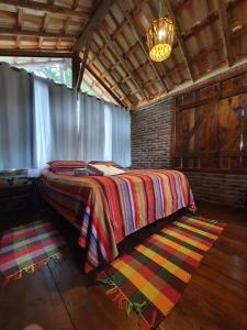 um quarto com uma cama com um cobertor colorido em Chalé Rústico - Retiro Andaluz em Moeda