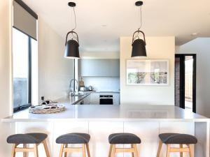 a kitchen with a large white island with stools at Broadbeach Inverloch in Inverloch