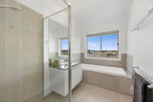a bathroom with a shower and a tub and a window at City & Surf Getaway in Grovedale +17 photos