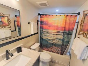 a bathroom with a shower curtain with a toilet and a sink at Bali Bungalow - Downtown Cocoa Beach in Cocoa Beach