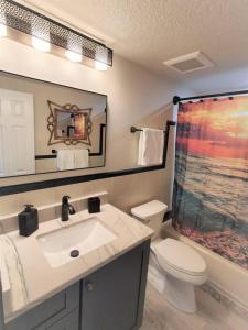 a bathroom with a sink and a toilet and a mirror at Bali Bungalow - Downtown Cocoa Beach in Cocoa Beach