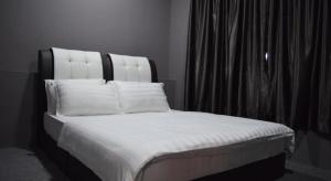 un letto con lenzuola e cuscini bianchi in una stanza di Times Traveller Lodge 2 a Kota Belud