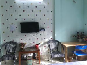 a room with two chairs and a table and a tv on a wall at Hotel Thien An in Yên Minh
