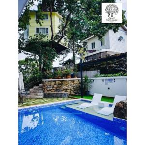 a swimming pool with two chairs and a house at CAMP TREEHOUSE • COTTAGE • POOL • JACUZZI in Antipolo