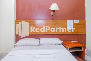 - un lit dans une chambre avec un panneau rouge partenaire dans l'établissement Hotel Sebelas At Jalan Palasari Mitra RedDoorz, à Bandung