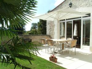 a patio with a table and chairs and an umbrella at Gîte familial avec piscine chauffée, jardin clos, équipement bébé, au cœur d'une propriété viticole. - FR-1-653-70 in Saint-Cybardeaux