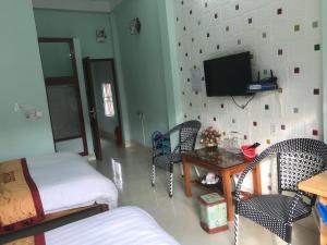 a living room with a tv and a table and chairs at Yen Minh Hotel Thien An in Na Thôn