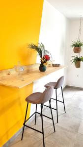 una cocina con 2 sillas y una pared amarilla en Le Marie-Agnès Appartement neuf de Standing en Fort-de-France