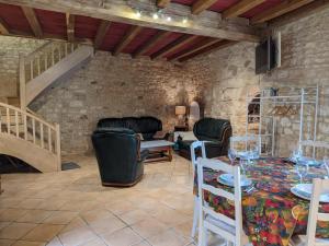 a living room with a staircase and a table and chairs at Gîte avec Piscine Chauffée, Jacuzzi et Jardin Privé - FR-1-653-156 in Charras