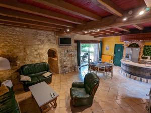a living room with green leather chairs and a table at Gîte avec Piscine Chauffée, Jacuzzi et Jardin Privé - FR-1-653-156 in Charras