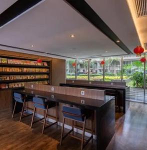 a library with a large wooden table and blue chairs at B Landmark Residence in Bandung