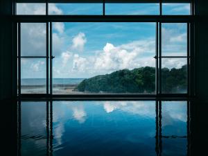 ein Fenster mit Blick auf das Meer und den Strand in der Unterkunft KAMENOI HOTEL Kii-Tanabe in Tanabe
