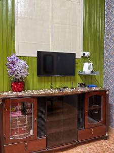 a entertainment center with a television on a green wall at Roomstay Budget Kuala Terengganu Desa Chendering Private Bathroom in Kuala Terengganu
