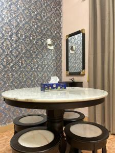 a table with three stools in a room with a mirror at Roomstay Budget Kuala Terengganu Desa Chendering Private Bathroom in Kuala Terengganu