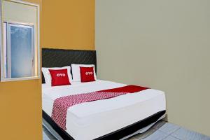 a bedroom with a bed with red pillows and a window at OYO 91825 Ayu Lestari Homestay in Nganjuk