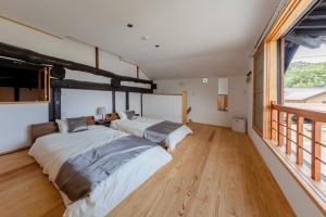 two beds in a room with wooden floors and windows at まるごの宿-耕- in Sukagawa