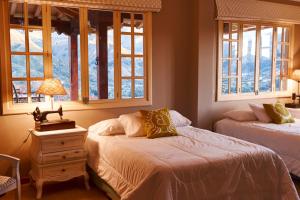 sypialnia z 2 łóżkami i stołem z lampką w obiekcie VillaBeatriz Lodge&Spa w mieście Vilcabamba