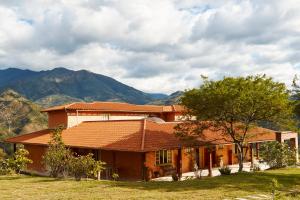 une maison avec un arbre et des montagnes en arrière-plan dans l'établissement VillaBeatriz Lodge&Spa, à Vilcabamba