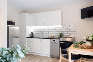 a kitchen with white cabinets and a wooden table at Surfrider 3 in Mollymook +8 photos