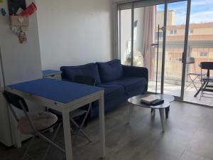 salon z niebieską kanapą i stołem w obiekcie Appartement avec Balcon Proche des Thermes, Étang et Commerces - Climatisé, Animaux Admis - FR-1-503-134 w mieście Balaruc-les-Bains