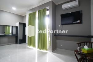 a living room with green curtains and a tv at Roemah Tebet Mitra RedDoorz in Jakarta +61 photos