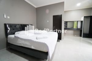 a bedroom with a large bed with white sheets at Roemah Tebet Mitra RedDoorz in Jakarta