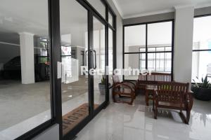 a lobby of a building with benches and windows at Roemah Tebet Mitra RedDoorz in Jakarta