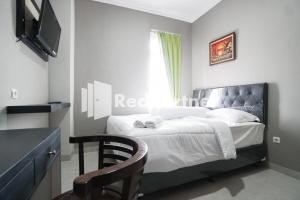 a bedroom with a bed with a television and a chair at Roemah Tebet Mitra RedDoorz in Jakarta