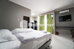 a bedroom with two beds and a flat screen tv at Roemah Tebet Mitra RedDoorz in Jakarta