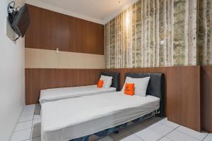 a bedroom with two beds with orange pillows at KoolKost near Cihampelas Walk in Bandung