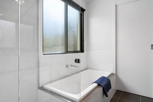 een badkamer met een bad en een glazen douche bij Sea View Beach House 11a in Torquay