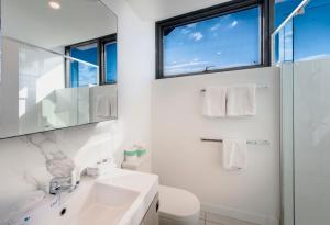 a white bathroom with a sink and a window at Hope Street Apartments by CLLIX in Brisbane