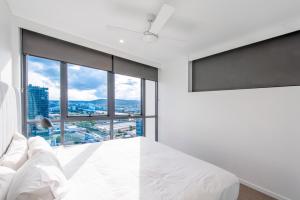 a bedroom with a white bed and a large window at Hope Street Apartments by CLLIX in Brisbane